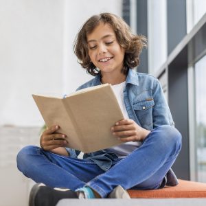 boy-reading-from-book-window