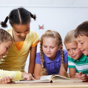 Portrait of pupils looking at page of encyclopaedia at reading lesson